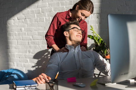 businessman recieving massage from his girlfriend at workplaceの写真素材