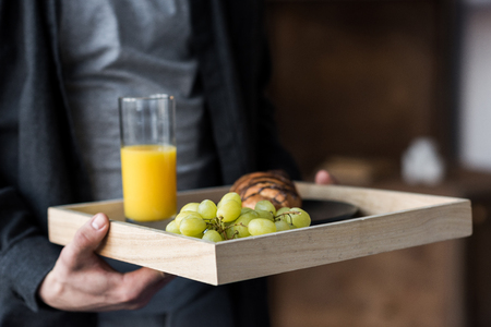 cropped image of man holding tray with breakfastの写真素材