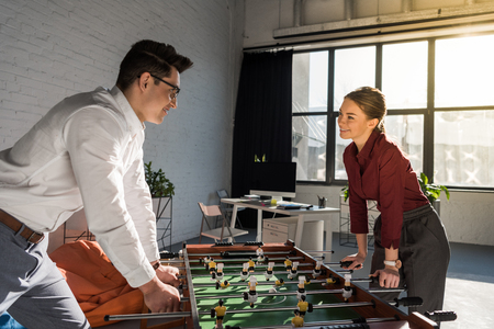 young business partners playing table football at modern officeの写真素材