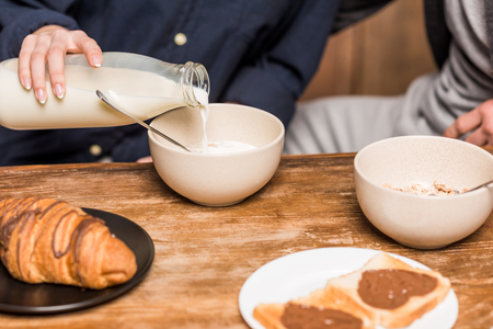 cropped image of girlfriend pouring milk in plateの写真素材