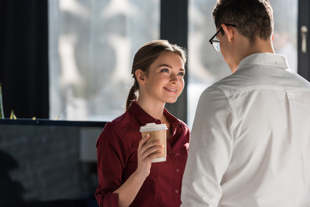 attractive young manageress with coffee to go flirting with colleagueの写真素材