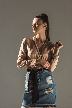 attractive girl posing in blouse and denim skirt, isolated on greyの写真素材