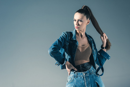 brunette young woman posing in trendy denim clothes, isolated on greyの写真素材