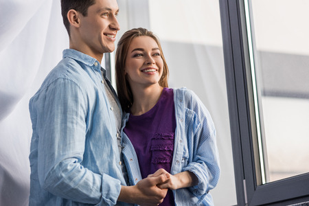 happy couple holding hands and looking awayの写真素材