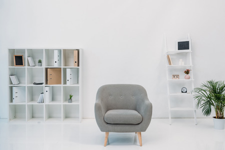 modern office interior with grey armchair and folders on shelvesの写真素材