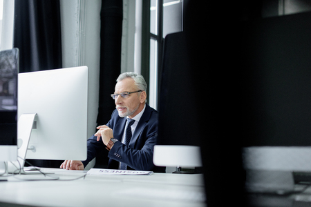 selective focus of senior businessman working on computer in officeの写真素材
