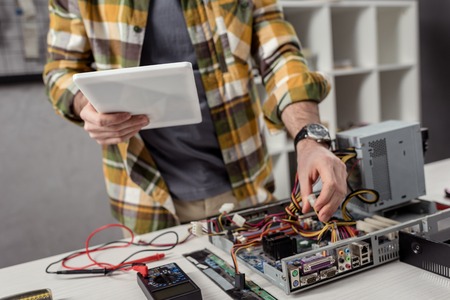 cropped image of man using digital tablet while fixing computerの写真素材