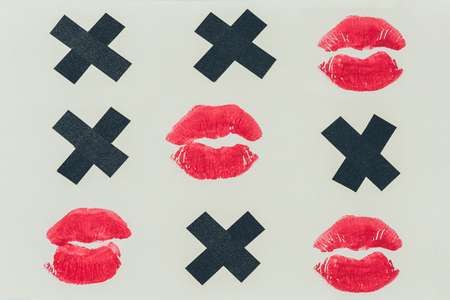 top view of tic-tac-toe with black crosses and lips prints isolated on whiteの写真素材