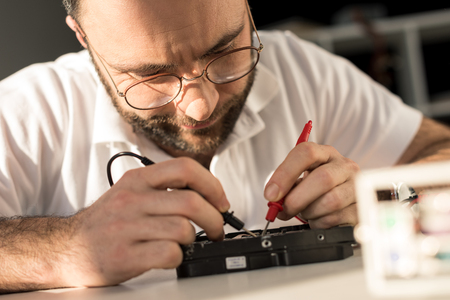 man using multimeter while testing hard disk driveの写真素材