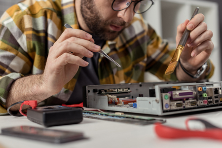 man using multimeter and whisk while fixing computer motherboardの写真素材