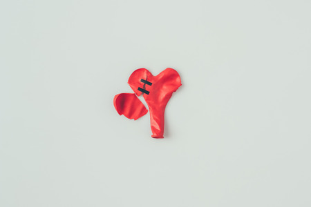 top view of broken heart shaped balloon with insulating tape isolated on whiteの写真素材