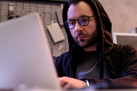man in glasses using laptop while sitting