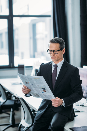 portrait of focused businessman reading newspaper in officeの写真素材
