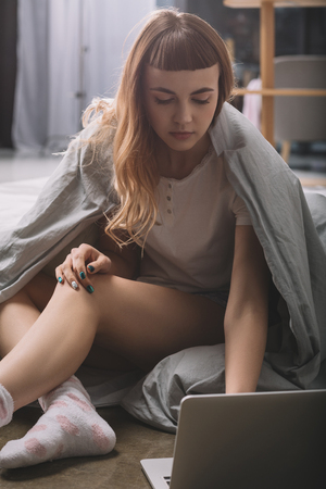 girl covering with blanket and using laptopの写真素材