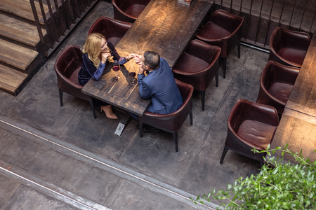 high angle view of adult couple holding hands on date at restaurantの写真素材