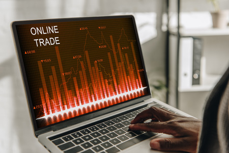 cropped view of african american businessperson using laptop with online trades website on screen