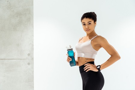 Young attractive sportive girl with sport bottle on white background