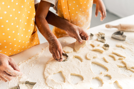 cropped image of african american mother and daughter preparing cookies with molds in kitchenの写真素材