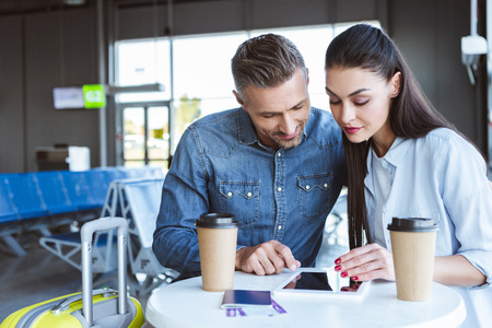 Adult couple sitting in airport and using digital tabletの写真素材