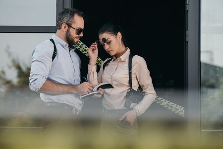 Partial view of female and male detectives review their records at crime sceneの写真素材