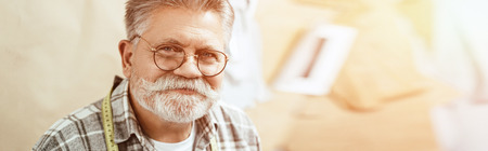 Portrait of happy mature craftsman in eyeglasses looking at camera in studioの写真素材