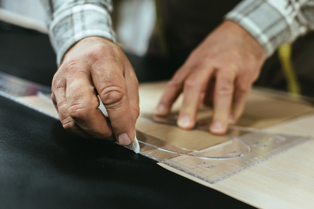 Cropped image of handbag craftsman making measurements on leather at workshopの写真素材