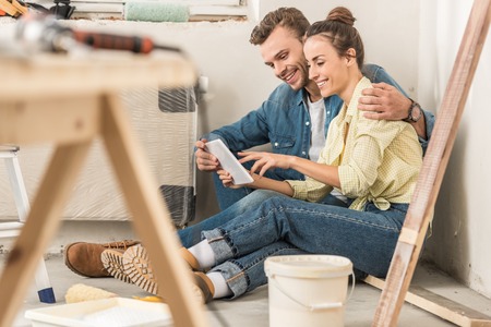 Happy young couple using digital tablet during renovation in new houseの写真素材