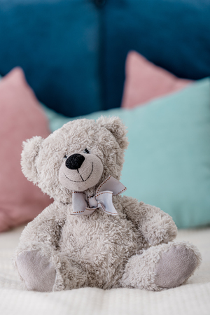 Close up vertical view of teddy bear sitting on the bed with pillows on backgroundの写真素材