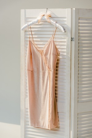 Close up of silk nightie with lace hanging on white room dividerの写真素材