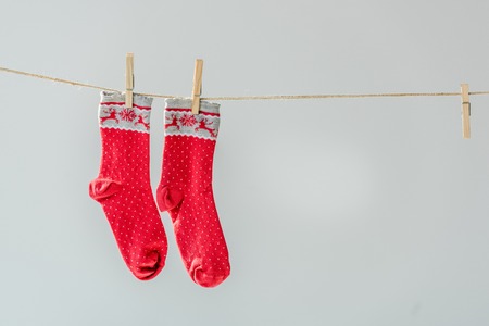 Close up of red festive winter socks hanging on clothesline with clothespins isolated on greyの写真素材
