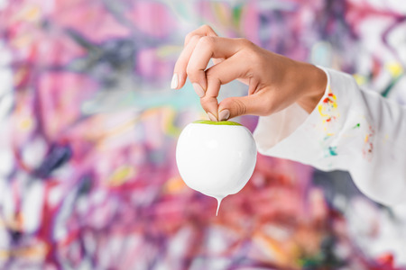 Close up of female hand holding white painted appleの写真素材