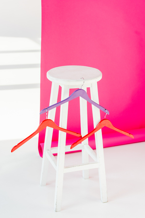Multicolored painted hangers with white wooden chair and pink wallpaperの写真素材