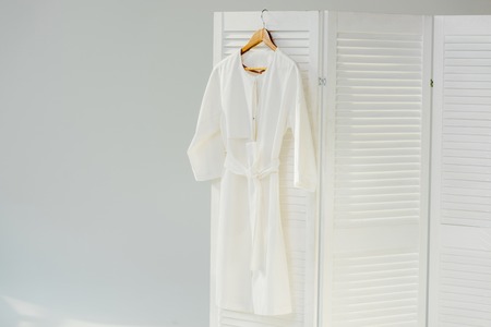 Elegant white dress hanging on wooden room divider