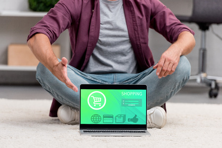 Cropped view of man pointing at laptop with online shopping illustrationの写真素材