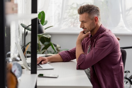 Man sitting on chair and working on laptop at workplace