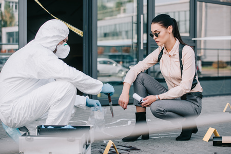 Criminologist shows knife as a murder weapon to female detectiveの写真素材
