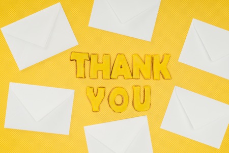 thank you lettering in cookies with white envelopes isolated on yellow backgroundの写真素材