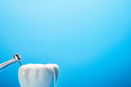 close up view of dental drill and white tooth model on blue background, dentistry conceptの写真素材