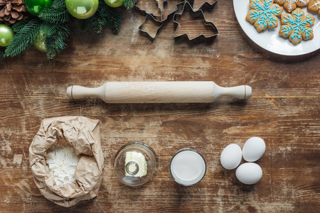 flat lay with ingredients for christmas cookies, wreath and rolling pin on wooden tabletopの写真素材
