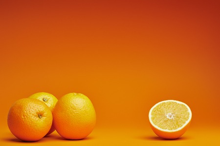 close-up view of whole and halved oranges on orange backgroundの写真素材