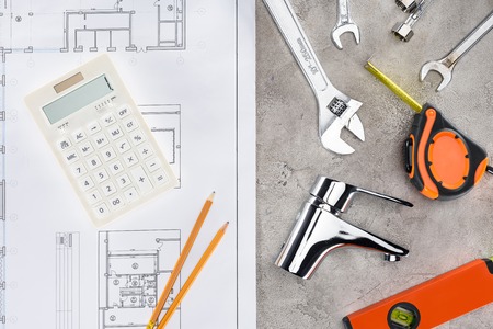 top view of building plan with various tools and calculator on concrete surface