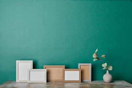 photo frames and vase with eucalyptus branch on table green backgroundの写真素材