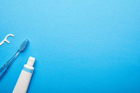 top view of dental floss, toothbrush and toothpaste arranged on blue backdrop, dentistry conceptの写真素材