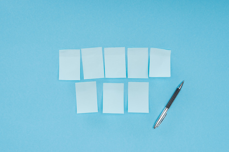 eight blank sticky notes with pen isolated on blue background