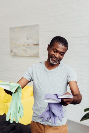 handsome smiling african american man holding rubber gloves