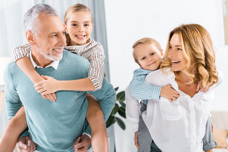 laughing grandparents doing piggyback ride to adorable grandchildren at home