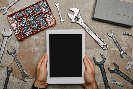 cropped view of laborer using digital tablet on table with different carpentry toolsの写真素材