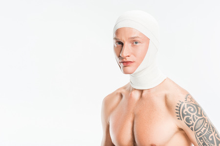 adult handsome man with bandages over head after plastic surgery isolated on whiteの写真素材