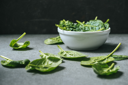 Flat lay of organic spinach leaves near white bowl with spinachの写真素材