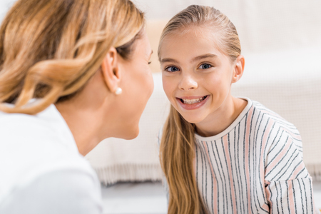close up view of laughing kid looking at camera and her grandmother at homeの写真素材
